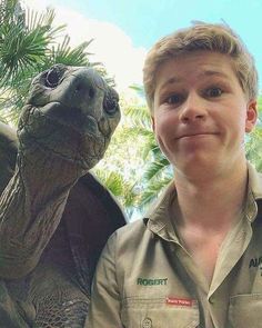 a boy standing next to a statue of a turtle