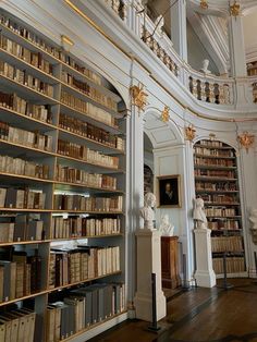 a room filled with lots of books next to a tall white column covered in statues