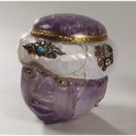 a purple glass vase with gold trimmings and jewels on it's head