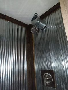 a shower head in the corner of a room with corrugated walls and metal coverings