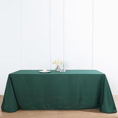 a table with a green cloth on it and white flowers in vases next to it