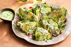 a white plate topped with brussel sprouts next to a bowl of dressing