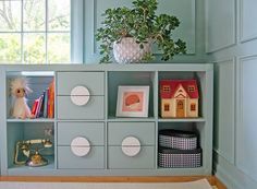 a shelf filled with books and toys next to a window