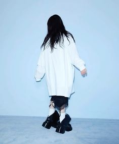 a woman standing in front of a blue wall with her back turned to the camera