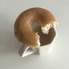 a half eaten donut sitting on top of a white cup