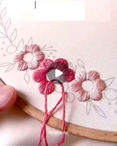 a video demonstrating how to make an embroidered flower on a piece of fabric with yarn