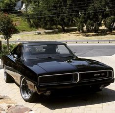 a black muscle car parked in front of a house