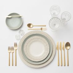 a white table setting with goldware and silverware