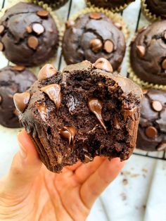 a chocolate muffin is being held up by someone's hand