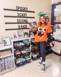 a woman in an orange shirt and black leggings holding up a book