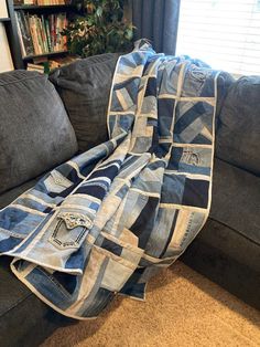 a blue and white blanket sitting on top of a couch next to a book shelf