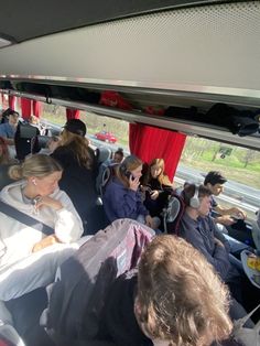 people are sitting in the back of a bus with red curtains on it and one person is taking a photo