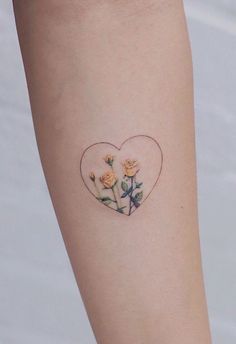 a small heart shaped tattoo with roses on the inside of it's left arm