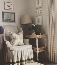 a living room with pictures on the wall and a chair next to a table in front of a window