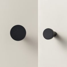 two black round knobs on the side of a white wall next to each other