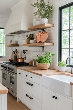 a kitchen with white cabinets and open shelving on the wall above the stove top