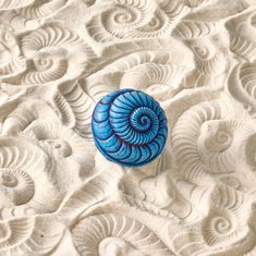 a blue shell sitting on top of sand covered in waves and swirly shapes,