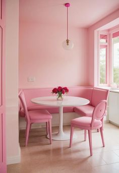 a white table with pink chairs and a vase of flowers on top of the table