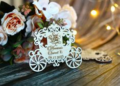 a wooden carriage ornament sitting on top of a table next to some flowers