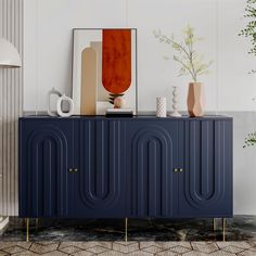 a blue cabinet with art on top and vases sitting on it's sides