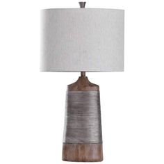 a wooden table lamp with a white shade on the top and silver metal trim around it