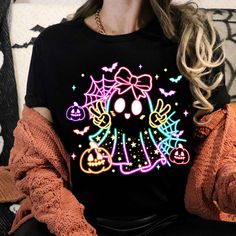 a woman sitting down wearing a black shirt with an image of a ghost on it