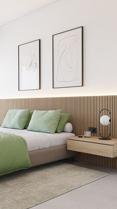 a bedroom with two framed pictures above the bed and green pillows on the headboard