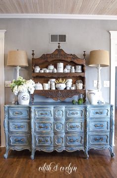 a blue dresser with two lamps on top of it