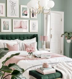 a bedroom with green walls and pictures on the wall above the bed, along with pink flowers