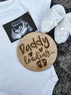 a baby bodysuit with the words daddy loading on it next to shoes and a photo