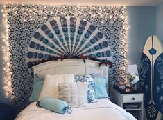 a white bed topped with lots of pillows next to a wall covered in string lights