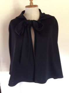 a woman's black cape with a bow on it