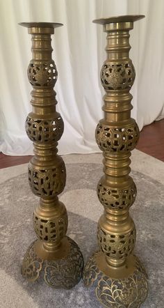 two metal candlesticks sitting next to each other on top of a round table