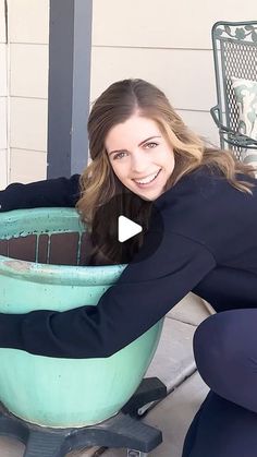 a woman kneeling down next to a green tub