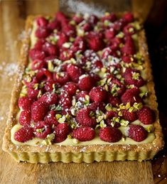 raspberry and pistachio tart on a wooden cutting board