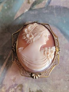 This is a vintage, cameo brooch/pendant with a filigree frame. It is oval and is stamped 1/20 12 K. All sales are final.  The cameo measures a bit over 1.5 inches in length, not including the bale. If you have a wish list or are looking for something specific, please ask. I may have exactly what you are looking for. As always please convo me with any questions or concerns regarding this item or with any international shipping questions. Unfortunately I do not accept returns or grant refunds. All shipping fees include handling fees. If you would like to combine shipping costs for more than one item, I would be happy to do so if you convo me before purchase. Purchasing my item means you have read, understood and will abide by my policies. Sorry, I do not accept trades. A bit about reserving Vintage Oval Brooches For Wedding, Oval Brooch For Vintage Events, Vintage Cameo Brooches For Vintage Events, Heirloom Style Oval Filigree Brooch, Vintage Oval Wedding Brooches, Antique Cameo Brooches For Wedding, Antique Oval Wedding Brooches, Heirloom Oval Filigree Brooch, Ornate Cameo Brooches For Anniversary