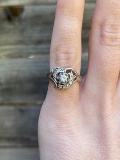 a close up of a person's hand with a ring on their finger and a wooden background