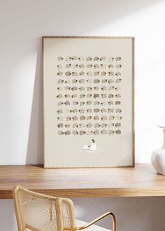 a white vase sitting on top of a wooden table next to a framed animal print