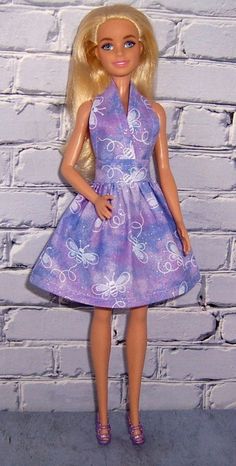 a barbie doll wearing a purple dress and shoes standing in front of a brick wall