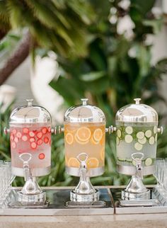 three different types of drinks are on a glass tray in front of some plants and trees