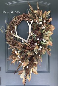 a wreath with antlers, flowers and leaves on it is hanging from the front door