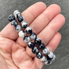 "Polished beads made from orca agate (thought to be a variety of blue chalcedony). 8mm Bracelets Sized: 6.50 - 6.75\" Our crystals and minerals are natural, and some are shaped by hand. Because each is unique and one of a kind, some may come with small chips or imperfections. Any appearances of cracks are one of the natural characteristics of this crystal or mineral and not because of damage. We select all crystals and minerals by hand. We choose the most unique and highest quality we can find. Adjustable Casual Agate Stretch Bracelet, Casual Adjustable Agate Stretch Bracelet, Casual Agate Beaded Bracelets With Round Beads, Casual Agate Beaded Bracelets, Handmade Casual Agate Stretch Bracelet, Casual Round Agate Beaded Bracelets, Casual Hand-strung Agate Bracelet, Casual Black Agate Beaded Bracelets, Orca Agate