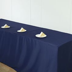 three white plates sitting on top of a blue table cloth covered table with gold trim