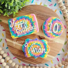 three decorated birthday cookies sitting on top of a wooden board next to sprinkles