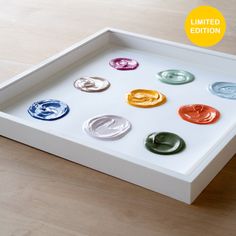 a white tray with six different colored buttons on the bottom and one in the middle