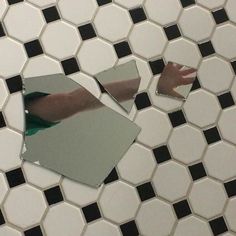 a person's reflection in a mirror on a tiled floor with black and white tiles