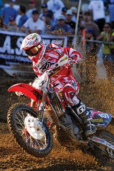 a man riding on the back of a red dirt bike in front of a crowd