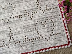 a crocheted dishcloth with the word love written on it next to pink flowers