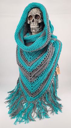 a crocheted skull wearing a blue and gray scarf with fringes on it