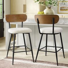 two stools in front of a kitchen counter with flowers on the table and an area rug